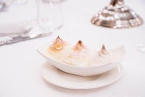 Genießen Sie die beliebtesten Kompositionen von W. A. Mozart, gespielt von Musikanten in historischen Kostümen. Salzburger Nockerln als Dessert auf einem weißen Teller mit Puderzucker bestäubt.